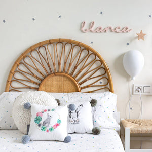 "An image of a cane headboard, featuring a woven design made of light brown cane material. The headboard is attached to a bed frame and is shown against a white wall with natural light illuminating the texture of the cane. The headboard has a simple and elegant design that adds a touch of natural warmth and texture to the bedroom.""Get a good night's sleep in style with this attractive and functional cane wooden headboard."